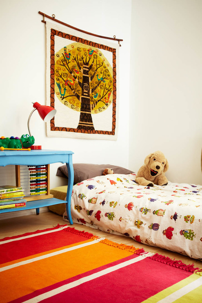 Eclectic gender-neutral kids' room in Toronto with white walls and light hardwood floors.
