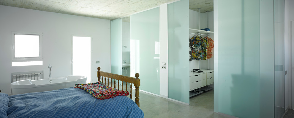 Photo of a mid-sized contemporary master bedroom in Other with white walls and concrete floors.