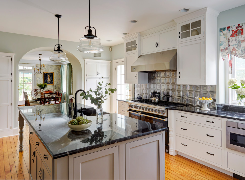 Inspiration for a large country l-shaped kitchen in Philadelphia with a farmhouse sink, white cabinets, quartzite benchtops, metallic splashback, metal splashback, stainless steel appliances, with island, shaker cabinets, medium hardwood floors and orange floor.