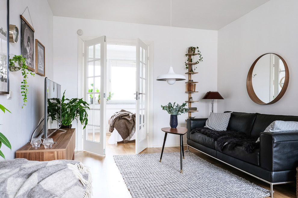 Photo of a mid-sized scandinavian enclosed living room in Gothenburg with white walls, no fireplace, a freestanding tv, medium hardwood floors and brown floor.