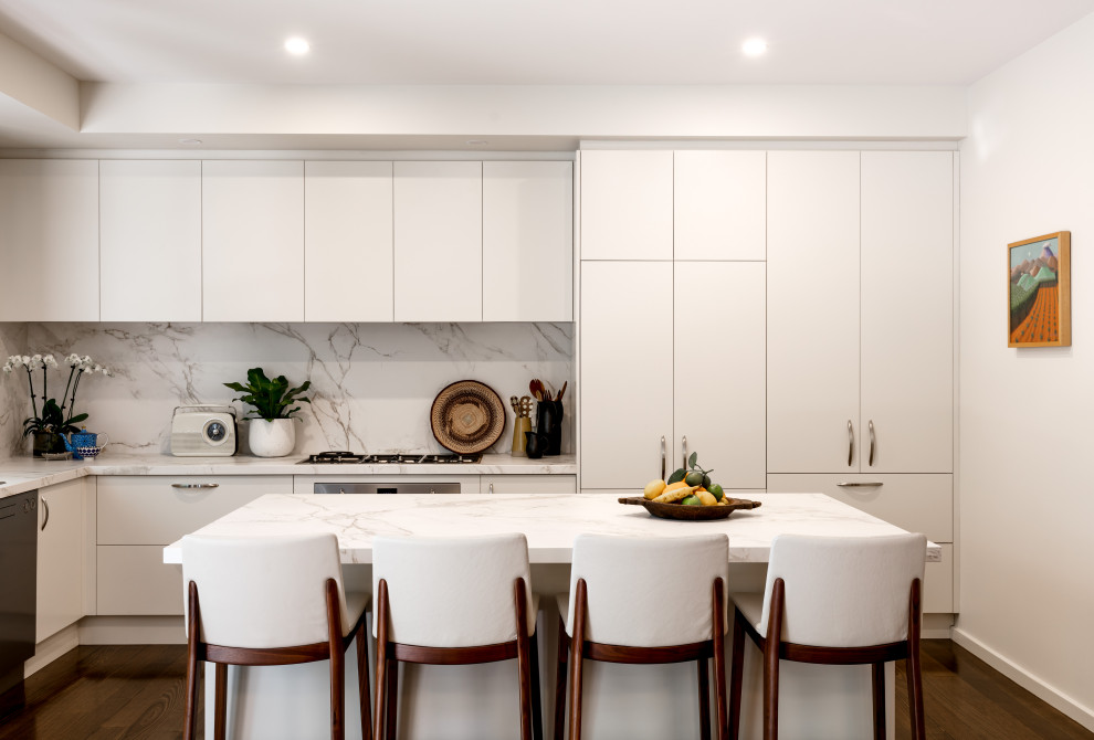 This is an example of a mid-sized contemporary kitchen in Melbourne with an undermount sink, white cabinets, quartz benchtops, white splashback, stainless steel appliances, medium hardwood floors, with island, brown floor and white benchtop.