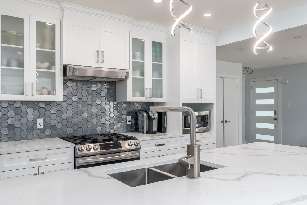 Inspiration for a transitional kitchen remodel in Edmonton with shaker cabinets, white cabinets, quartzite countertops, gray backsplash, cement tile backsplash, stainless steel appliances, an island and white countertops
