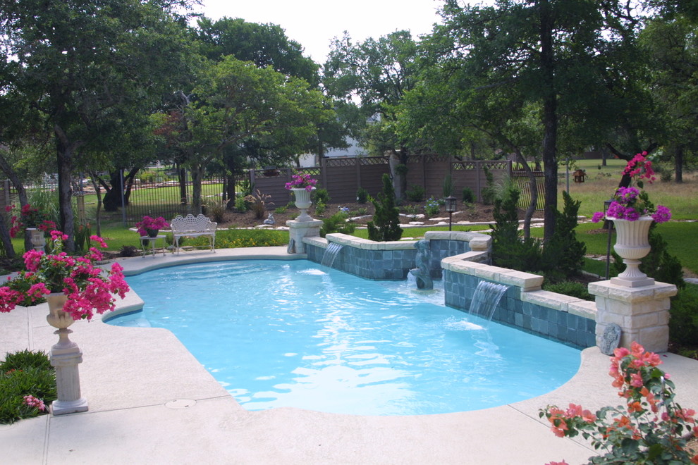 Large mediterranean backyard rectangular lap pool in Austin with a water feature and concrete slab.