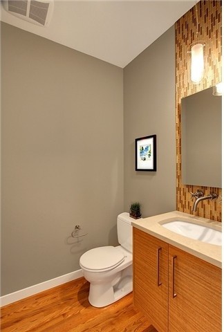 Photo of a mid-sized contemporary 3/4 bathroom in Seattle with an undermount sink, flat-panel cabinets, engineered quartz benchtops, glass tile, grey walls, medium hardwood floors, light wood cabinets, brown floor, a two-piece toilet, multi-coloured tile and beige benchtops.