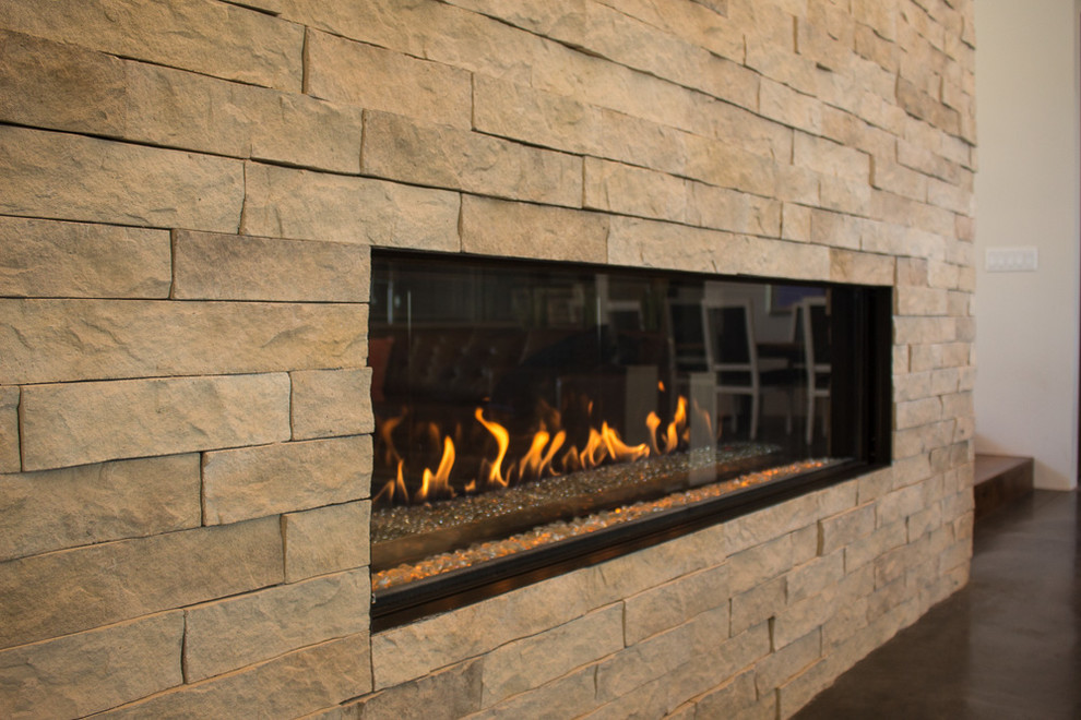 Inspiration for a mid-sized modern open concept family room in Salt Lake City with white walls, concrete floors, a standard fireplace, a stone fireplace surround and a wall-mounted tv.