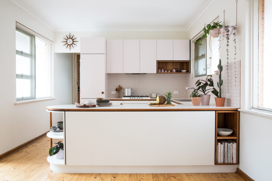 Photo of a small midcentury u-shaped open plan kitchen in Adelaide with flat-panel cabinets, laminate benchtops, white splashback, ceramic splashback, white appliances and light hardwood floors.