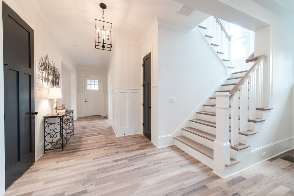 Photo of a mid-sized arts and crafts foyer in Charlotte with white walls, light hardwood floors, a single front door and beige floor.