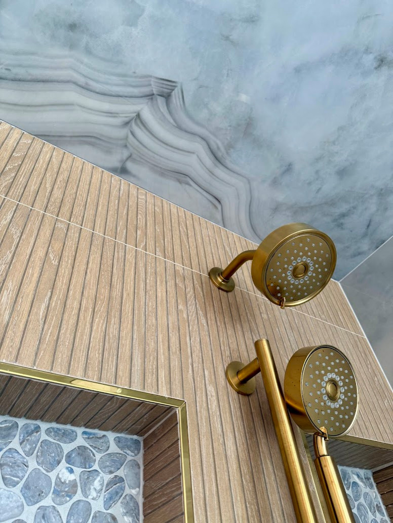 Organic Modern bathroom design in Rockville, MD featuring a spa-like atmosphere with large-format porcelain tile, natural wood vanities, and minimalist black hardware. This primary bath renovation by