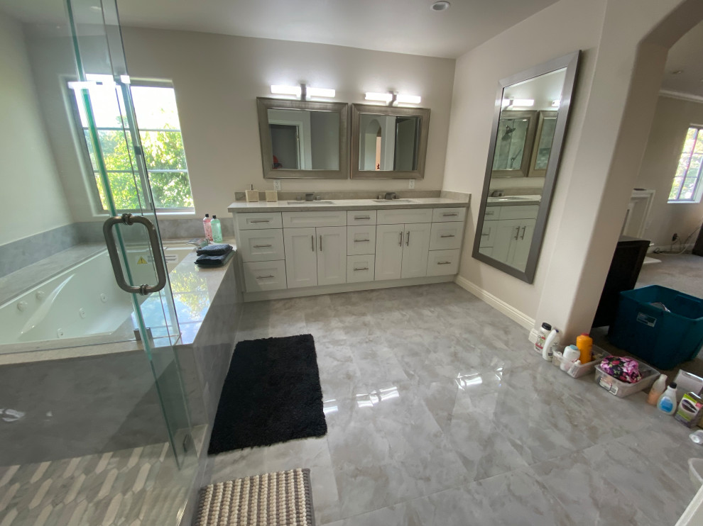 Large eclectic master bathroom in Los Angeles with shaker cabinets, white cabinets, a drop-in tub, a corner shower, a one-piece toilet, porcelain tile, cement tiles, a drop-in sink, quartzite benchtops, grey floor, grey benchtops, a double vanity and a built-in vanity.