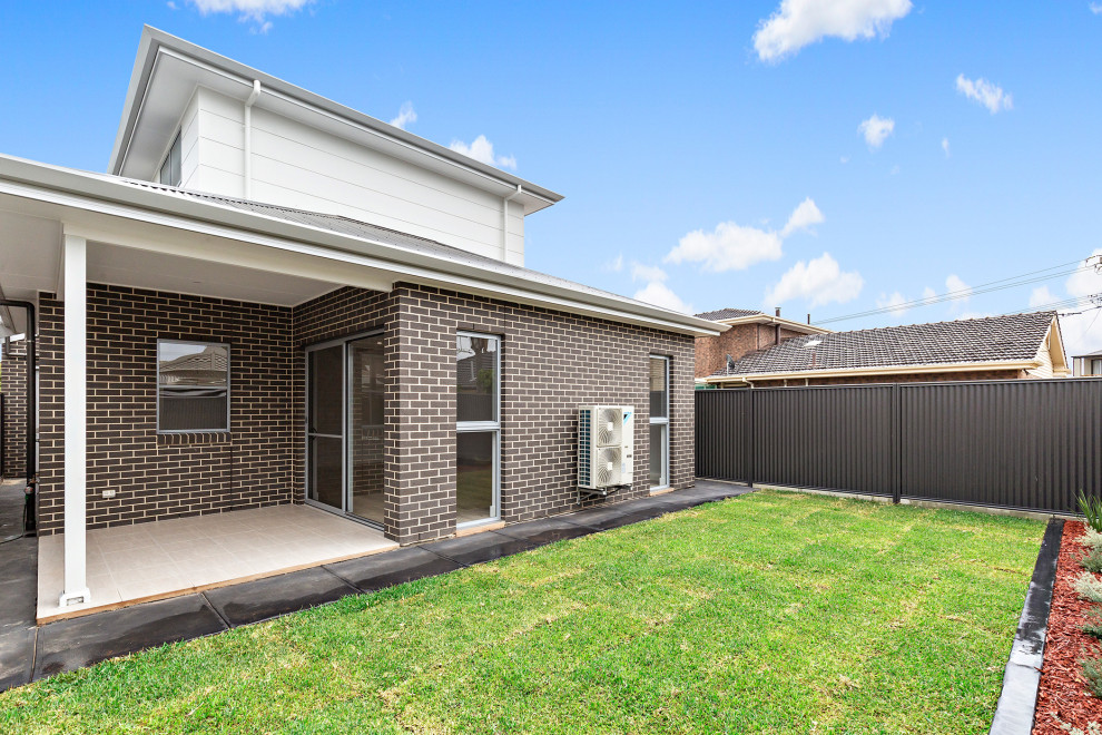 Mid-sized two-storey brick multi-coloured house exterior in Adelaide with a hip roof, a metal roof and a black roof.