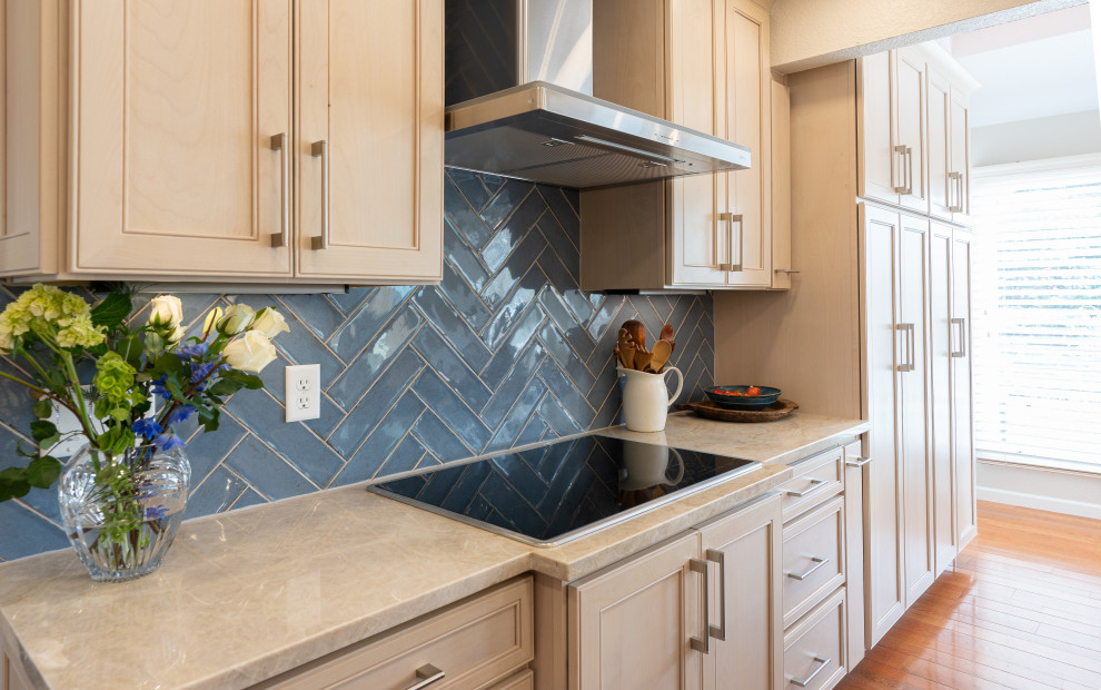 Mid-sized transitional l-shaped eat-in kitchen in Denver with a single-bowl sink, flat-panel cabinets, blue cabinets, quartzite benchtops, blue splashback, porcelain splashback, stainless steel appliances, medium hardwood floors, with island, brown floor, beige benchtop and vaulted.