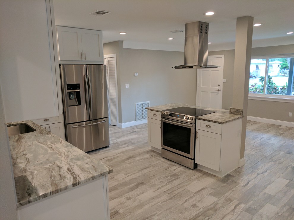 Enclosed kitchen - mid-sized transitional l-shaped light wood floor and gray floor enclosed kitchen idea with an undermount sink, shaker cabinets, white cabinets, granite countertops, multicolored backsplash, matchstick tile backsplash, stainless steel appliances, gray countertops and an island