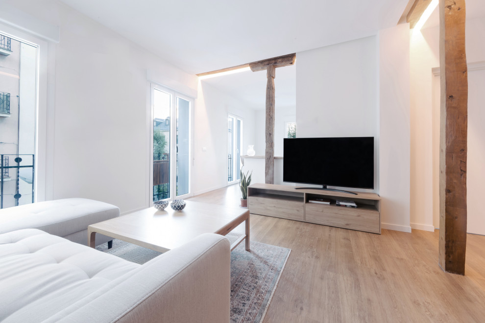 This is an example of a small contemporary open concept family room in Madrid with white walls, vinyl floors, a freestanding tv, brown floor, recessed and brick walls.