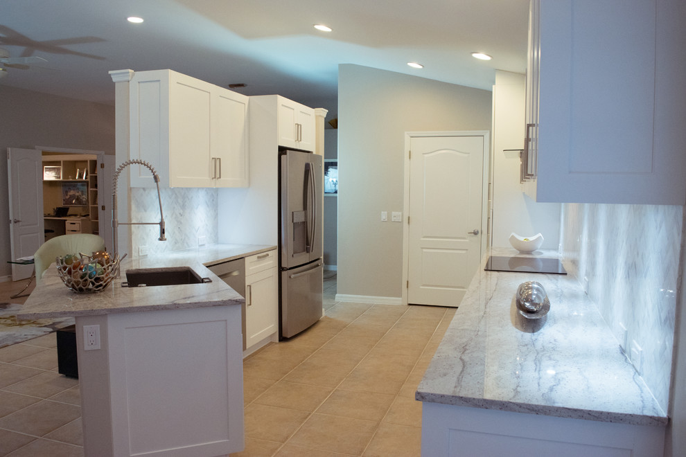 Eat-in kitchen - mid-sized transitional galley ceramic tile and beige floor eat-in kitchen idea in Miami with an undermount sink, shaker cabinets, white cabinets, granite countertops, gray backsplash, stone tile backsplash, stainless steel appliances and a peninsula