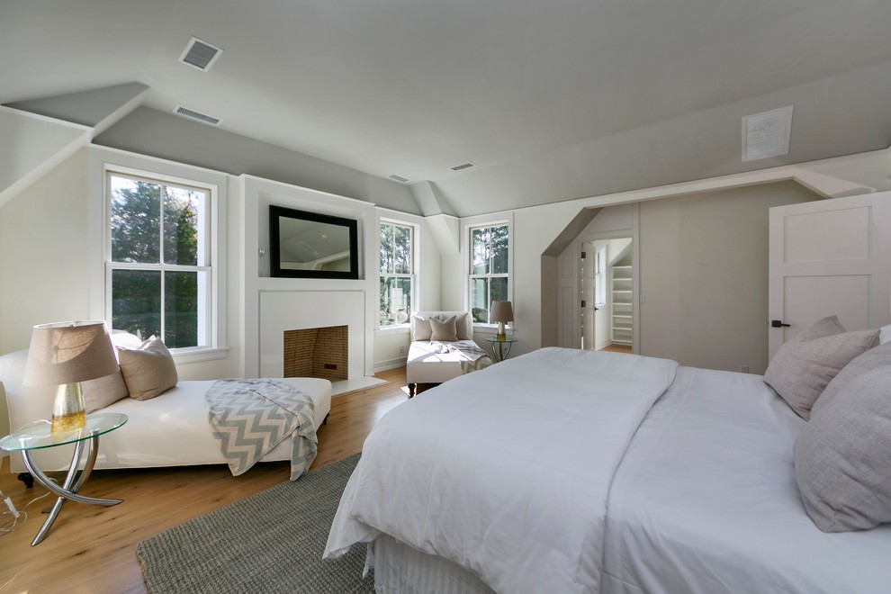Design ideas for a large contemporary master bedroom in New York with white walls, light hardwood floors, a standard fireplace and a plaster fireplace surround.