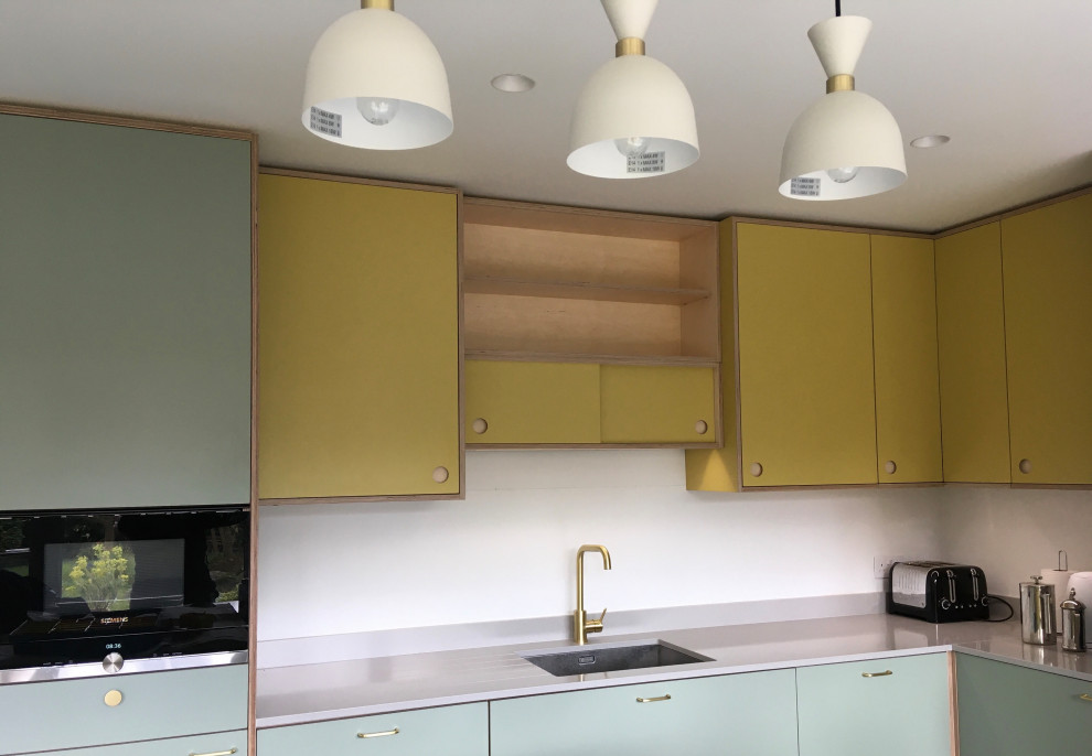 Réalisation d'une cuisine américaine encastrable vintage en L de taille moyenne avec un évier encastré, un placard à porte plane, un plan de travail en surface solide, une crédence blanche, une crédence en feuille de verre, un sol en carrelage de porcelaine, îlot, un sol gris et un plan de travail gris.