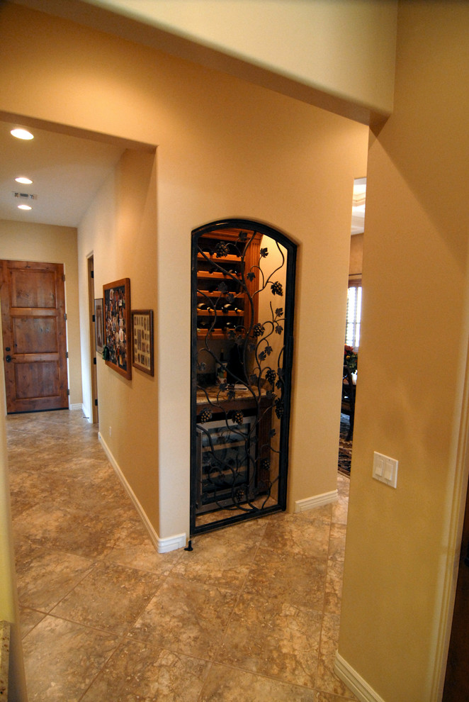 This is an example of a large traditional wine cellar in Phoenix with limestone floors and display racks.