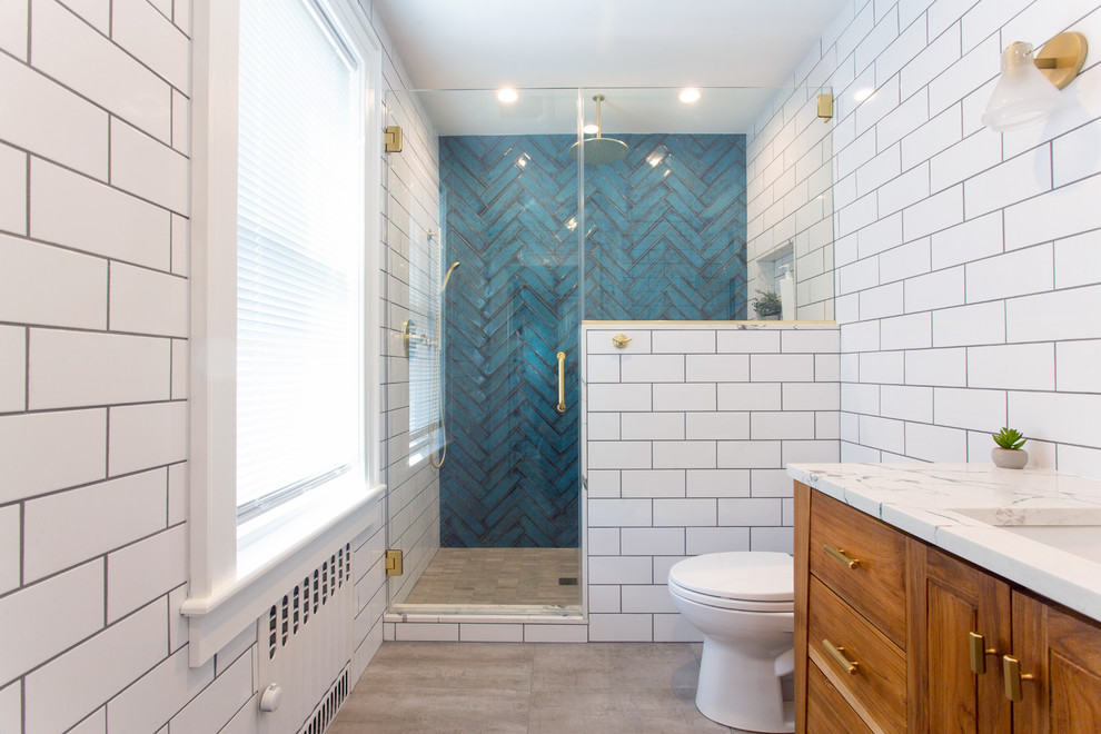 Inspiration for a mid-sized midcentury bathroom in New York with flat-panel cabinets, medium wood cabinets, an alcove shower, a two-piece toilet, white tile, subway tile, white walls, concrete floors, an undermount sink, quartzite benchtops, grey floor, a hinged shower door and white benchtops.