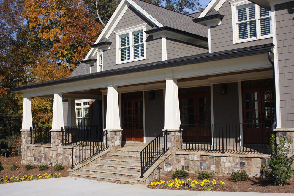 This is an example of a mid-sized traditional front yard verandah in Atlanta with a container garden, natural stone pavers and a roof extension.