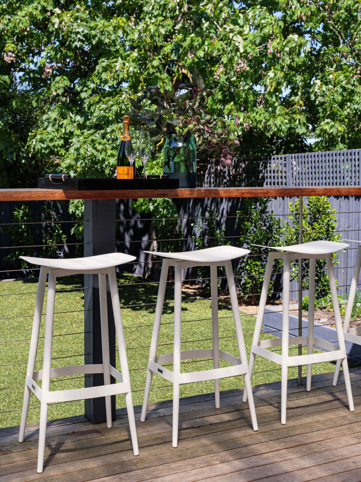 This is an example of a large transitional backyard deck in Melbourne with a pergola.