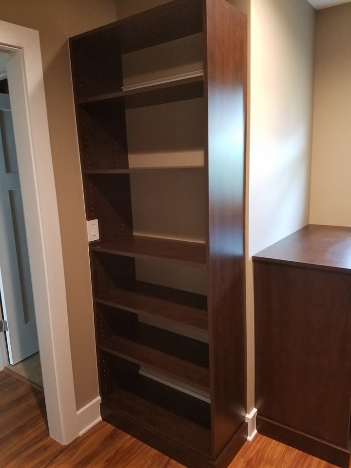 This is an example of a mid-sized transitional gender-neutral walk-in wardrobe in Jacksonville with flat-panel cabinets, dark wood cabinets, light hardwood floors and beige floor.