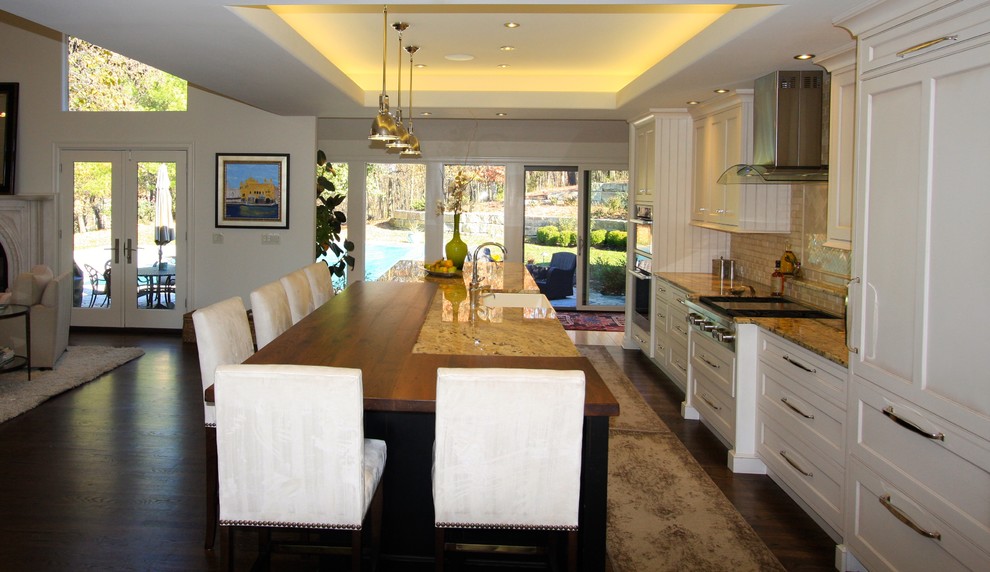 Example of a large transitional single-wall dark wood floor and brown floor open concept kitchen design in Kansas City with a farmhouse sink, recessed-panel cabinets, white cabinets, granite countertops, beige backsplash, paneled appliances, an island and multicolored countertops