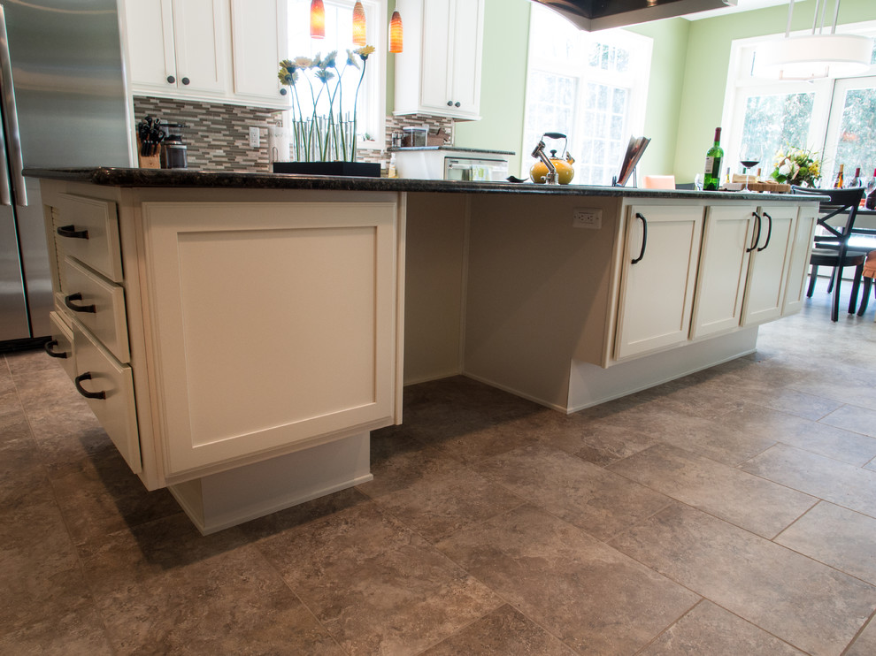 Large transitional u-shaped porcelain tile eat-in kitchen photo with an undermount sink, recessed-panel cabinets, white cabinets, granite countertops, multicolored backsplash, glass tile backsplash, stainless steel appliances and an island