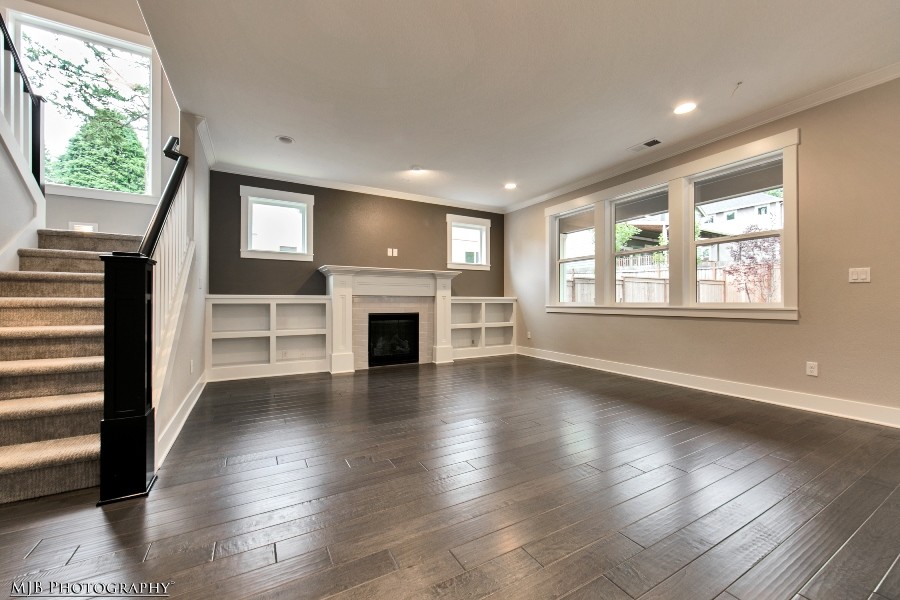 This is an example of an arts and crafts open concept family room in Portland with beige walls, dark hardwood floors, a standard fireplace and a tile fireplace surround.