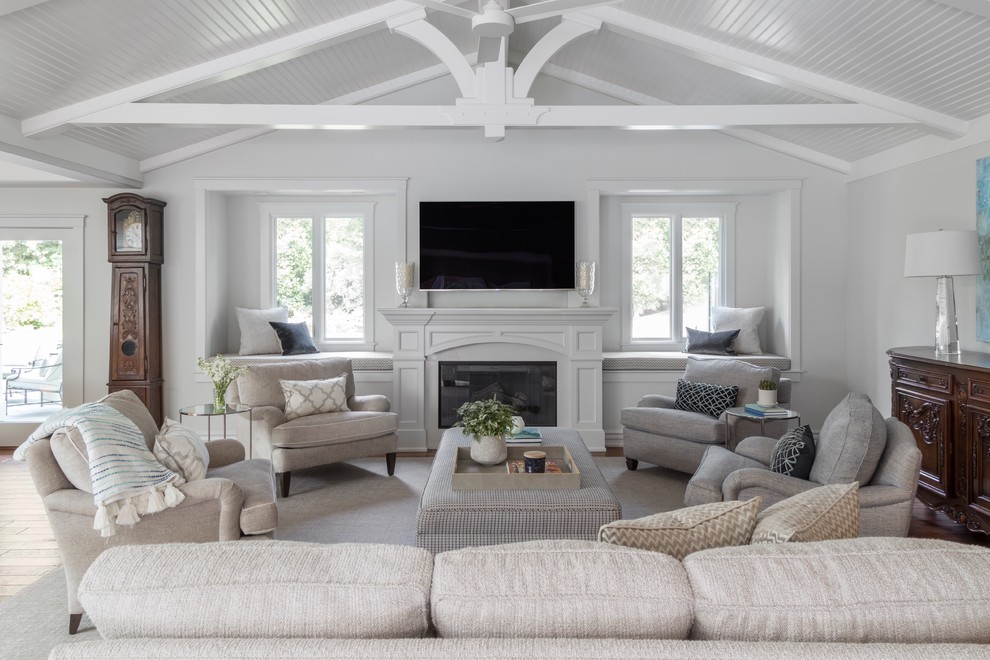 Inspiration for a large traditional open concept family room in San Francisco with medium hardwood floors, a standard fireplace, a wood fireplace surround, a wall-mounted tv, brown floor and white walls.