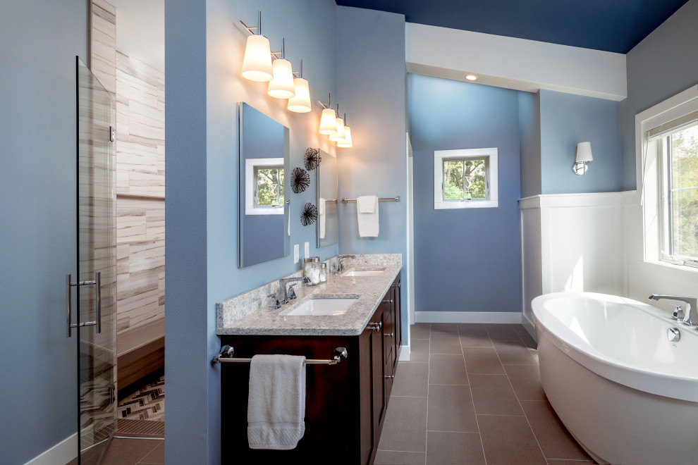 Design ideas for a mid-sized modern master bathroom in Milwaukee with a freestanding tub, a curbless shower, blue walls, engineered quartz benchtops, grey floor, a hinged shower door, an enclosed toilet, a double vanity, vaulted, decorative wall panelling, shaker cabinets, dark wood cabinets, gray tile, an undermount sink, grey benchtops and a built-in vanity.