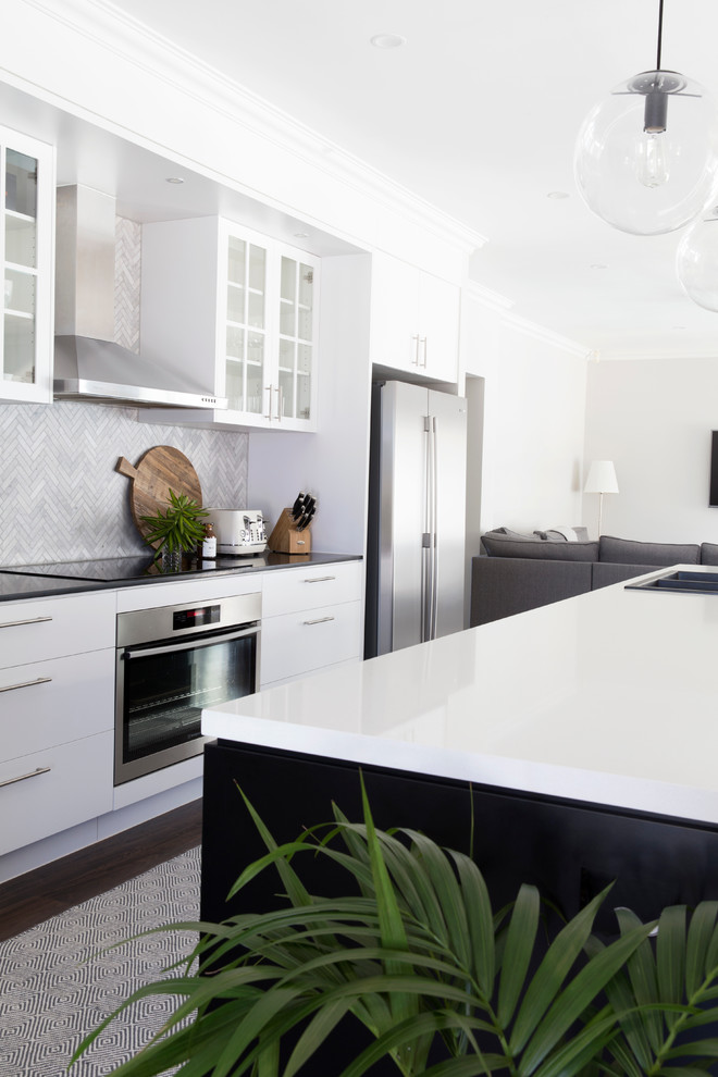 This is an example of a mid-sized contemporary galley eat-in kitchen in Gold Coast - Tweed with a drop-in sink, flat-panel cabinets, black cabinets, quartz benchtops, grey splashback, porcelain splashback, stainless steel appliances, dark hardwood floors and with island.