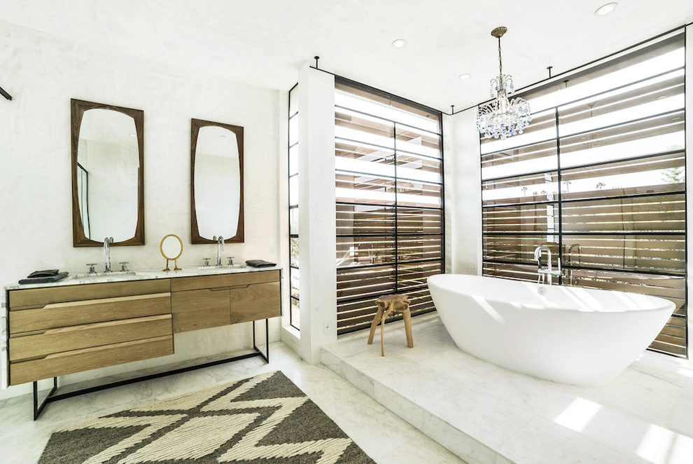 This is an example of a mid-sized master bathroom in Los Angeles with medium wood cabinets, a freestanding tub, a corner shower, white walls and porcelain floors.