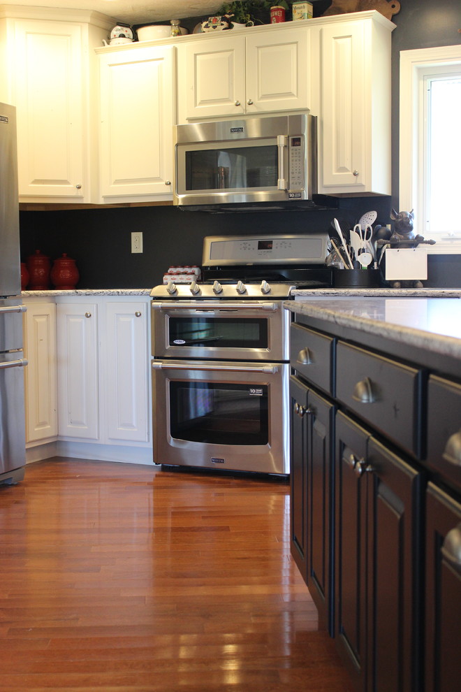 Example of a large mountain style l-shaped light wood floor open concept kitchen design in Chicago with a farmhouse sink, raised-panel cabinets, white cabinets, quartz countertops, stainless steel appliances and an island