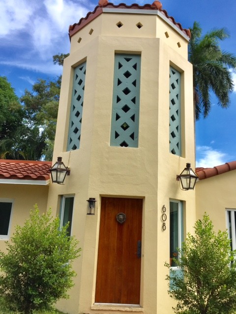 This is an example of a mid-sized mediterranean one-storey concrete yellow house exterior in Miami with a gable roof and a shingle roof.