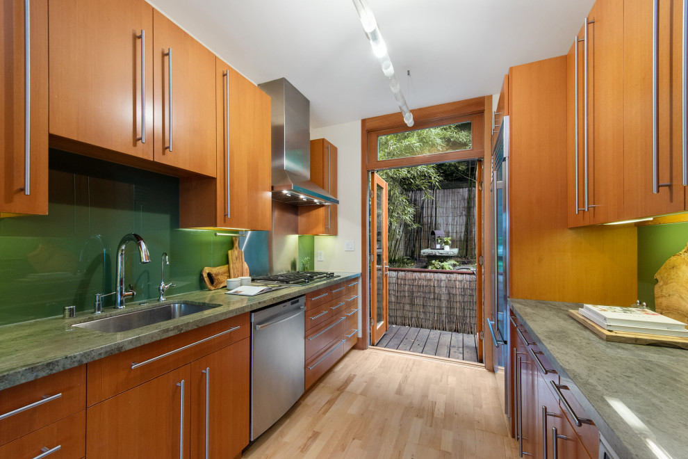 This is an example of a small asian galley separate kitchen in San Francisco with a single-bowl sink, flat-panel cabinets, light wood cabinets, marble benchtops, green splashback, glass sheet splashback, stainless steel appliances, light hardwood floors, no island, beige floor and green benchtop.