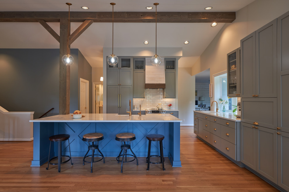 Photo of a mid-sized country l-shaped open plan kitchen in Seattle with an undermount sink, shaker cabinets, grey cabinets, quartz benchtops, white splashback, ceramic splashback, panelled appliances, medium hardwood floors, with island, brown floor, white benchtop and vaulted.