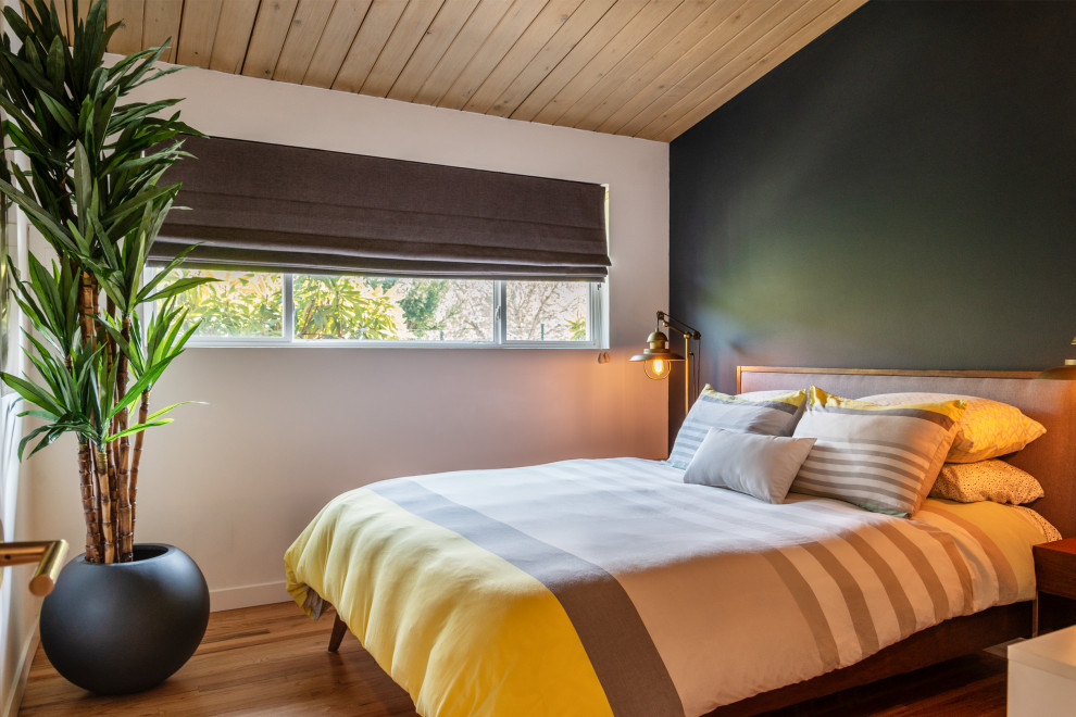 Aménagement d'une chambre d'amis rétro de taille moyenne avec un mur vert, parquet clair et un plafond en bois.