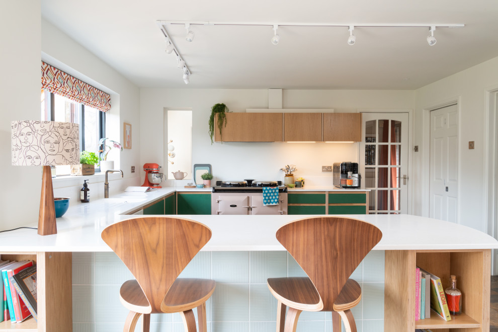 Design ideas for a medium sized midcentury u-shaped kitchen/diner in West Midlands with an integrated sink, flat-panel cabinets, green cabinets, composite countertops, white splashback, glass tiled splashback, coloured appliances, vinyl flooring, an island, multi-coloured floors and white worktops.