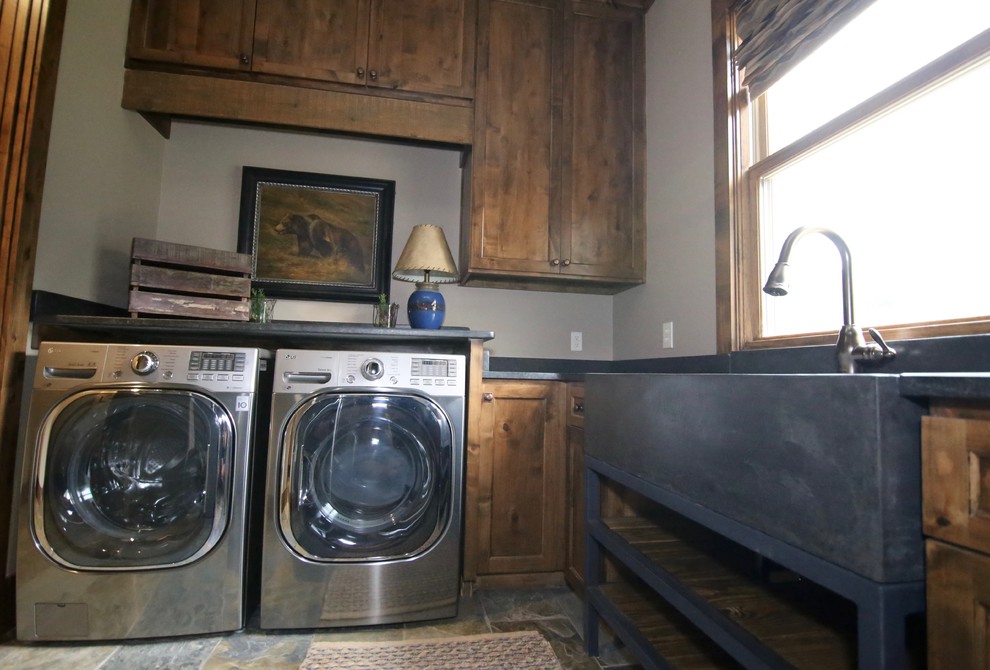 Design ideas for a mid-sized country laundry room in Dallas with a farmhouse sink, shaker cabinets, dark wood cabinets, soapstone benchtops, white walls, slate floors and a side-by-side washer and dryer.