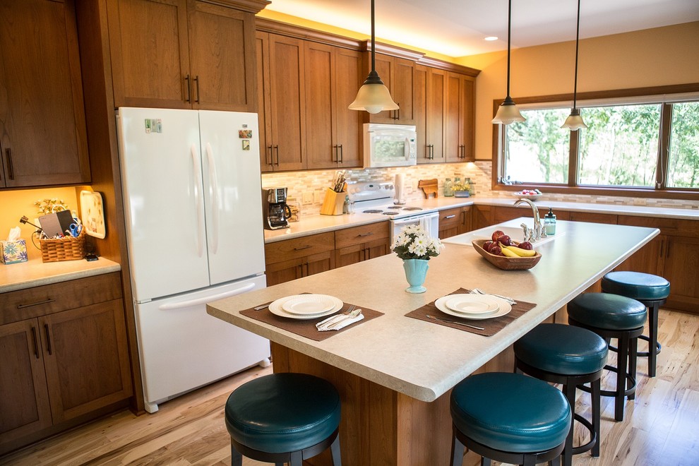 Large transitional l-shaped light wood floor eat-in kitchen photo in Cedar Rapids with a double-bowl sink, recessed-panel cabinets, medium tone wood cabinets, laminate countertops, multicolored backsplash, mosaic tile backsplash, white appliances and an island