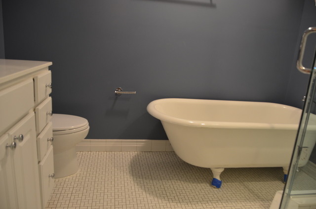 This is an example of a mid-sized traditional bathroom in DC Metro with raised-panel cabinets, beige cabinets, a claw-foot tub, a two-piece toilet, black and white tile, porcelain tile, blue walls, porcelain floors, an integrated sink, marble benchtops and white floor.