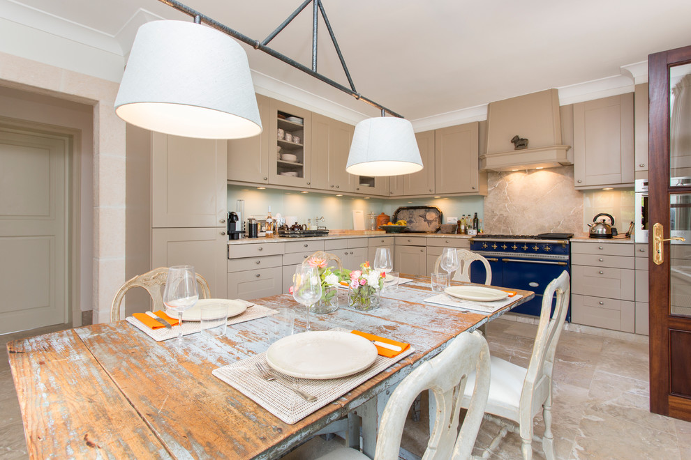 Country l-shaped eat-in kitchen in Palma de Mallorca with recessed-panel cabinets, beige cabinets, no island, beige splashback and coloured appliances.