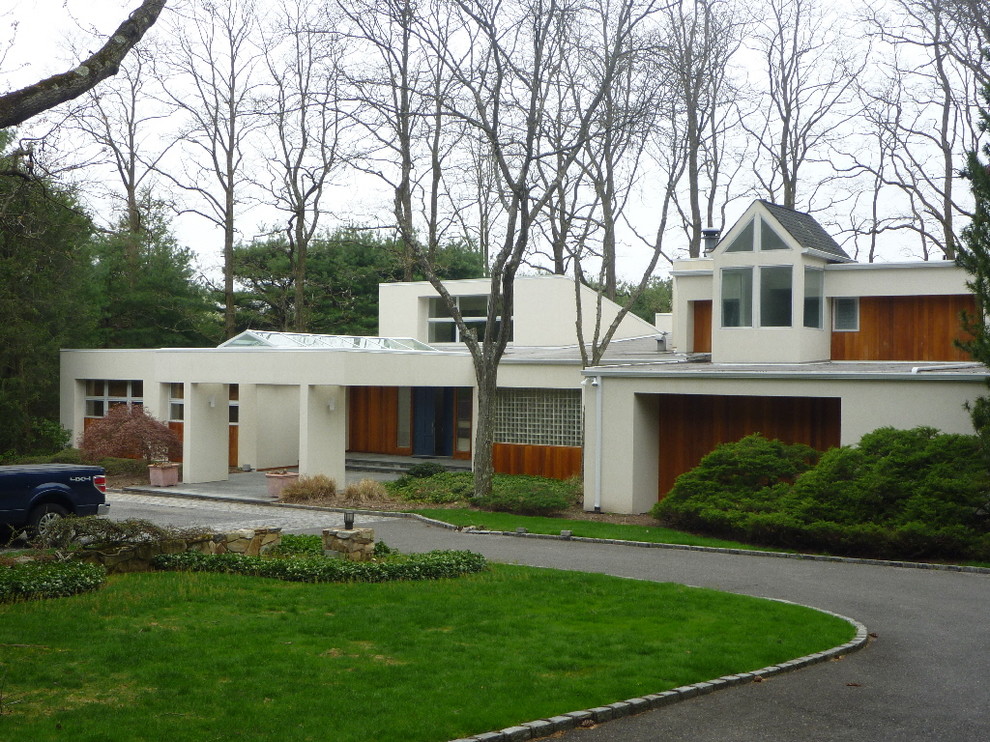 Expansive modern two-storey stucco beige house exterior in New York with a flat roof and a shingle roof.