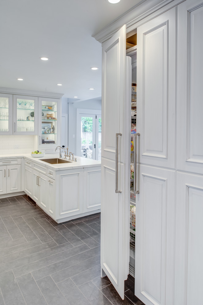 Inspiration for a traditional u-shaped kitchen in San Francisco with an undermount sink, raised-panel cabinets, white cabinets, quartz benchtops, white splashback, subway tile splashback, panelled appliances, grey floor, white benchtop and ceramic floors.