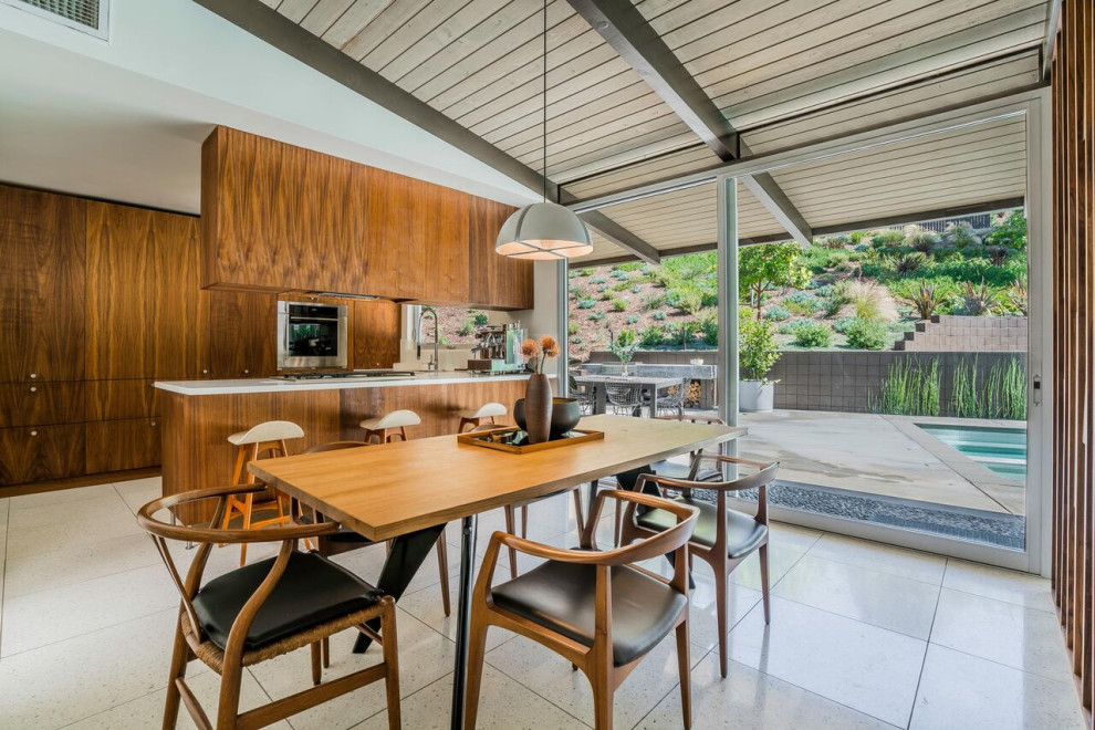 Inspiration for a mid-sized midcentury u-shaped eat-in kitchen in Los Angeles with a double-bowl sink, flat-panel cabinets, dark wood cabinets, solid surface benchtops, stainless steel appliances, terrazzo floors, a peninsula, white floor, white benchtop and exposed beam.