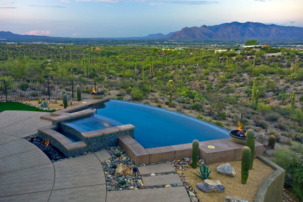 Mid-sized custom-shaped infinity pool in Phoenix with concrete slab.