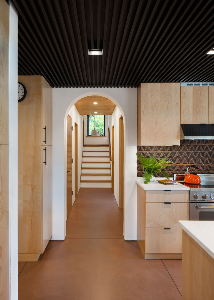 Moderne Wohnküche mit flächenbündigen Schrankfronten, hellen Holzschränken, Küchenrückwand in Metallic, Küchengeräten aus Edelstahl, Betonboden, Kücheninsel, orangem Boden, weißer Arbeitsplatte und Holzdecke in Boston