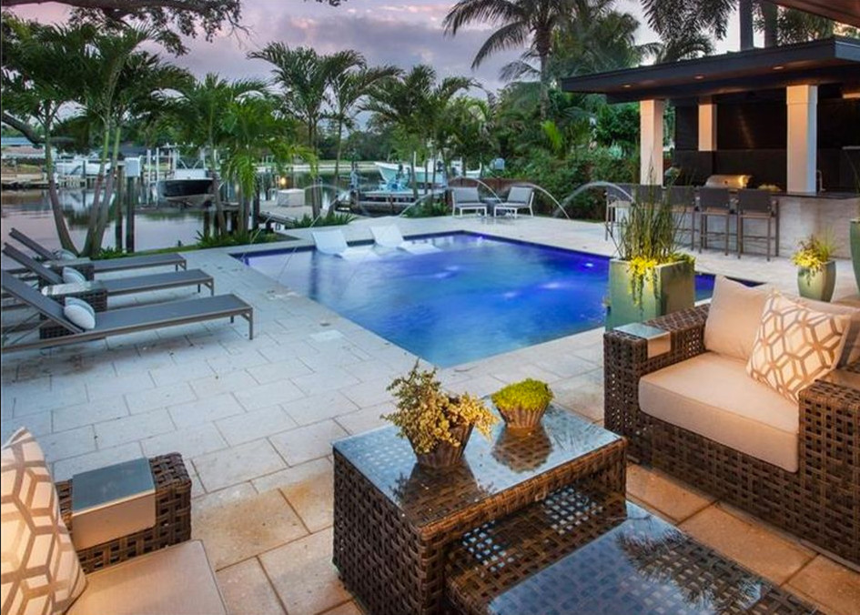 Inspiration for a large contemporary backyard rectangular lap pool in Tampa with a water feature and natural stone pavers.
