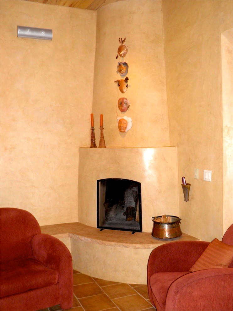 This is an example of an enclosed living room in Albuquerque with beige walls, terra-cotta floors, a corner fireplace and a stone fireplace surround.
