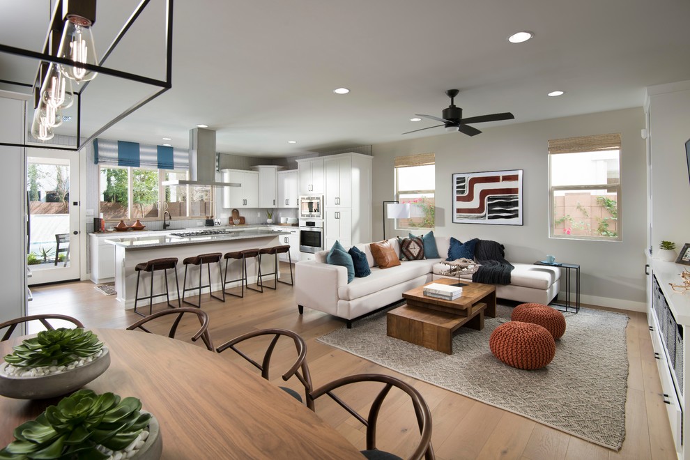 This is an example of a mid-sized transitional open concept living room in Phoenix with grey walls, light hardwood floors, beige floor and a built-in media wall.